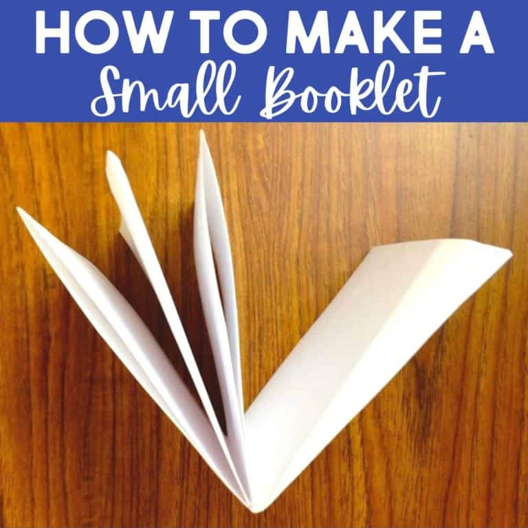 A few folded white sheets of paper forming a small booklet lie open on a wooden surface. Above, text reads Make a Small Booklet in large and script fonts on a blue background.