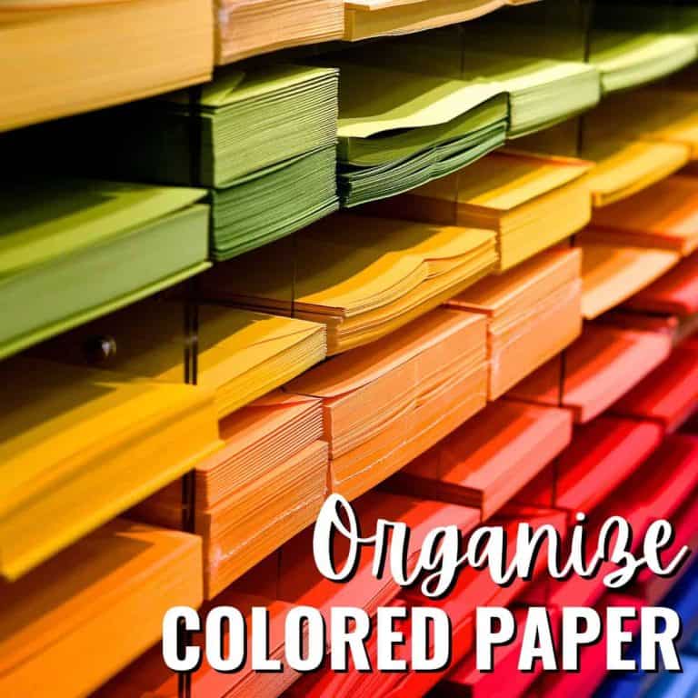 Stacks of colored paper organized by shade in horizontal slots, ranging from yellow and green to orange and red, showcase easy ways to Organize Colored Paper, with the phrase overlaid at the bottom right.