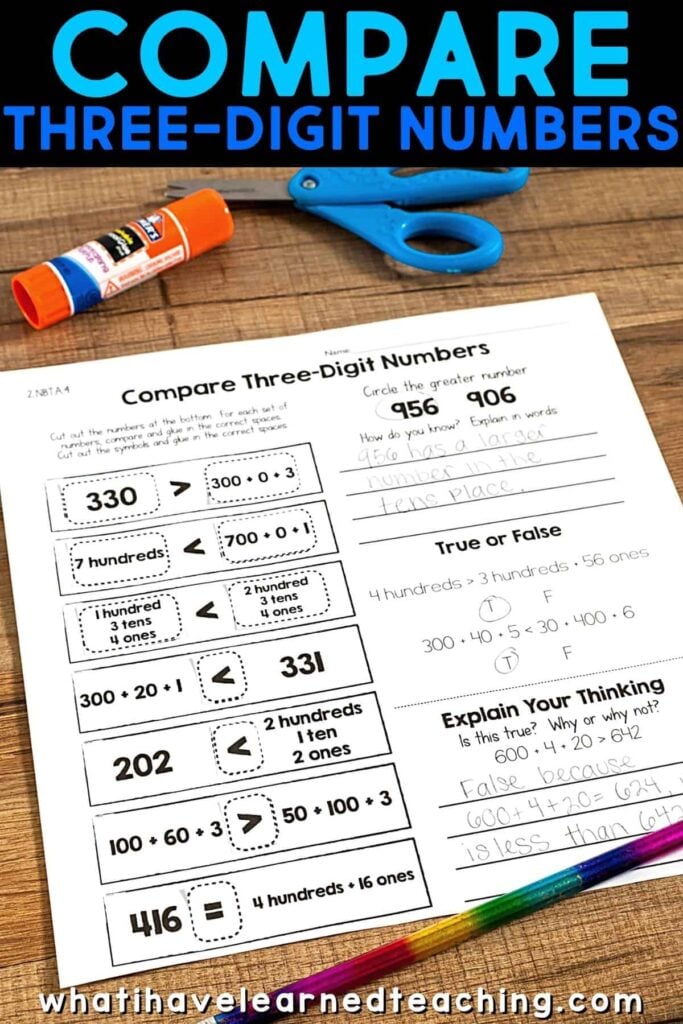 Cut and Paste Math Activities for 2nd Grade: Self-Checking 4 A worksheet titled Compare three digit numbers featuring math problems and cut-and-paste activities for second grade, surrounded by a glue stick, blue scissors, and colored pencils on a wooden desk. The website whatihavelearnedteaching.com is displayed at the bottom.