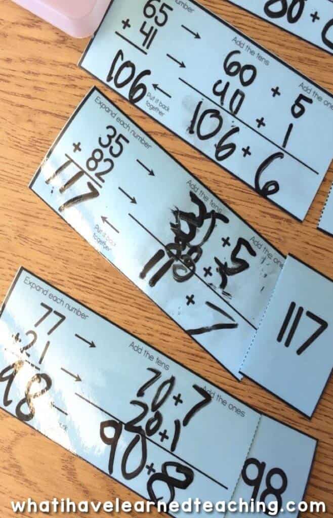 These Two-Digit Addition Math Stations help students use models and addition strategies such as a number line, breaking apart the addends, and base-10 blocks. They are easy to print, laminate, and cut apart and last year after year. This photo has students break apart the addends to add.