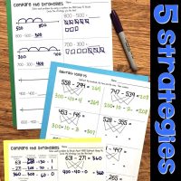 Four worksheets showing different subtraction strategies with numbers, equations, diagrams, and number lines are spread on a wooden surface with a purple marker nearby. The text 5 strategies is on the right in bold blue letters.