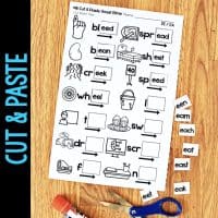 The Long Vowel Teams AI & AY Worksheets & Activities No-Prep Phonics Worksheets feature cut-and-paste onset-rime activities with pictures, words, and word endings like "ain" and "ay," plus scissors and glue on a wooden surface.