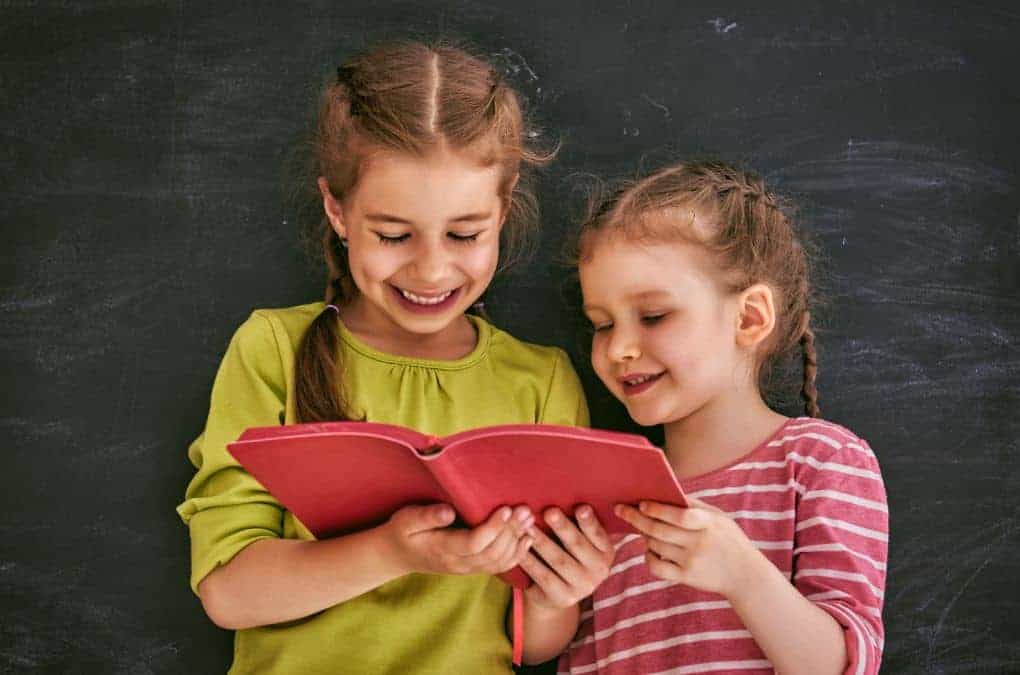 two girls talking about a book.