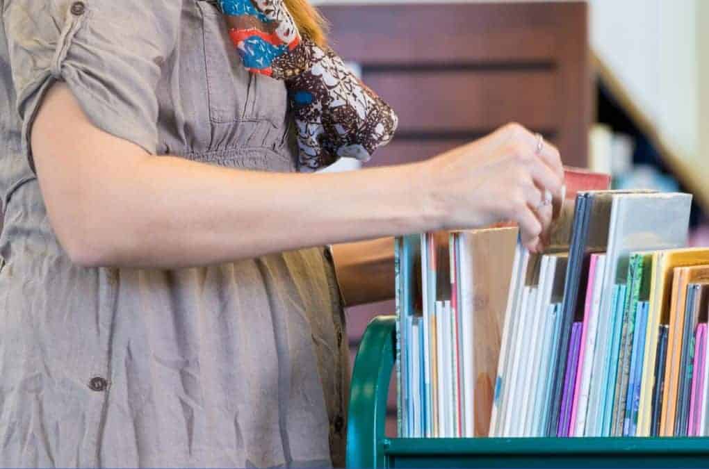 teacher going through a stack of books.