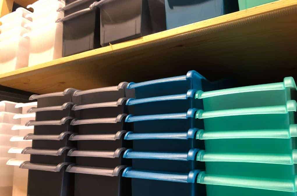 stack of storage bins in different colors on a shelf.